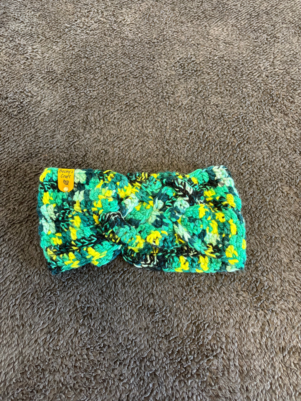 Green and yellow patterned headband on a gray surface