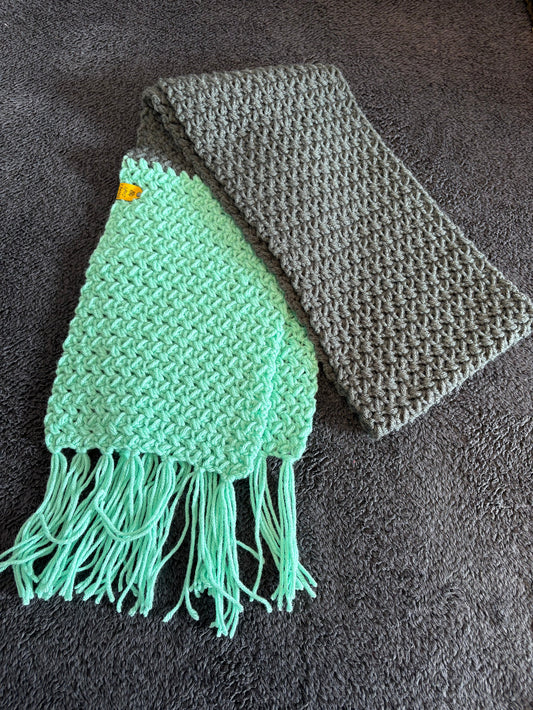 Gray and green knitted scarf on a dark textured surface