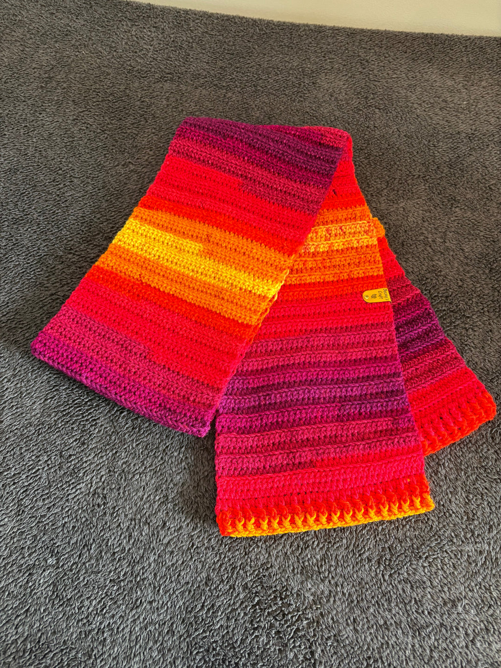 colorful striped crocheted scarf on a gray surface