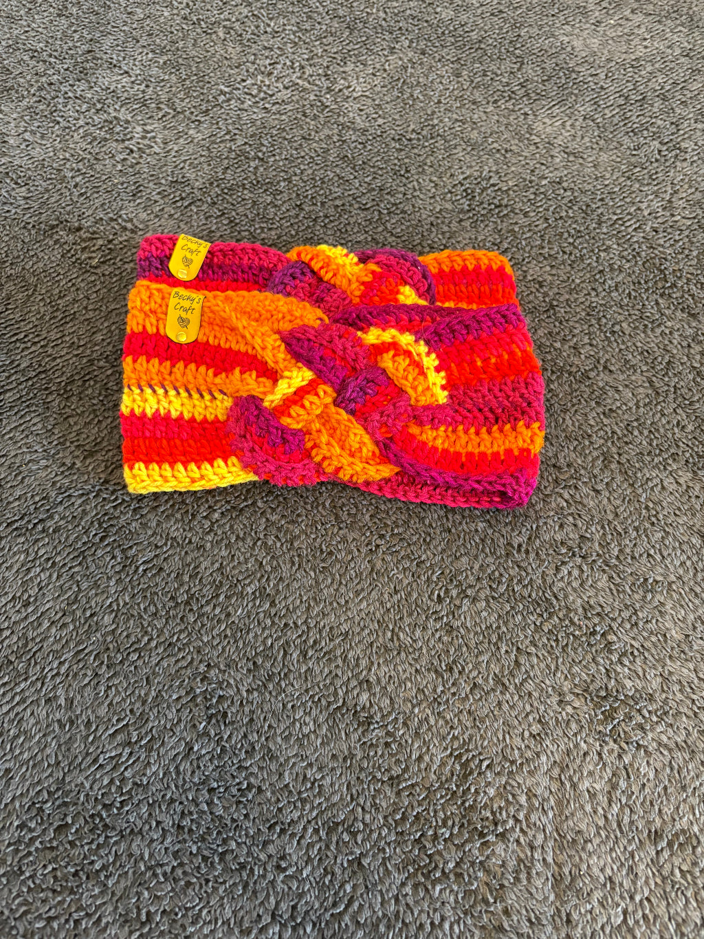 Crocheted Headband with red and yellow pattern on a gray surface