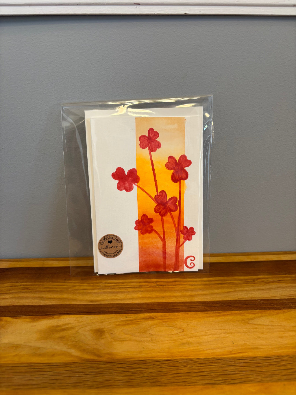 Card with floral design in a clear plastic sleeve on a gray surface