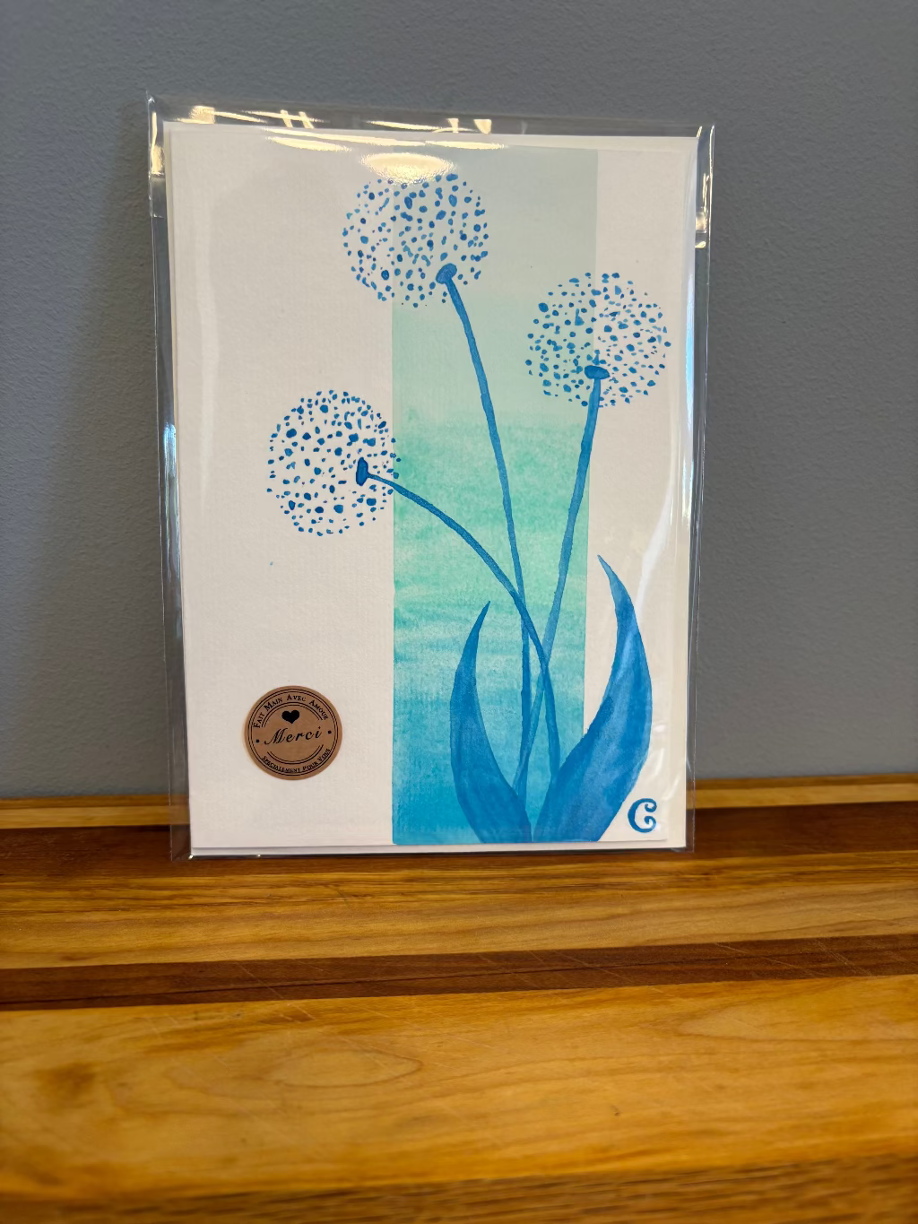 Card with blue floral design on a wooden surface and gray wall background